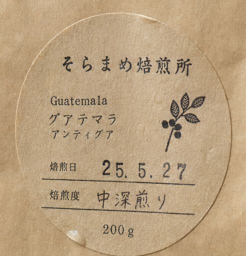 豆の袋の丸いラベル。産地と焙煎日、手書きの「中深煎り」の文字。