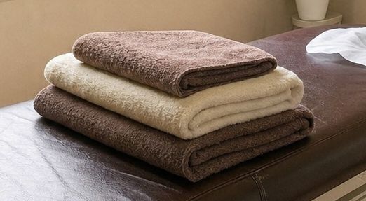 ベッドの上に畳んで重ねた、茶色と白のタオル。